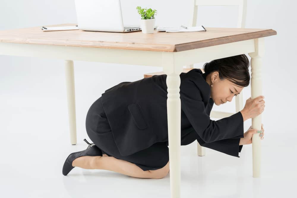 机の下に避難する女性